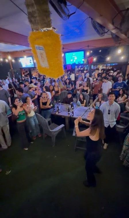 A guest dancing under a hanging pi&ntilde;ata as the crowd cheers