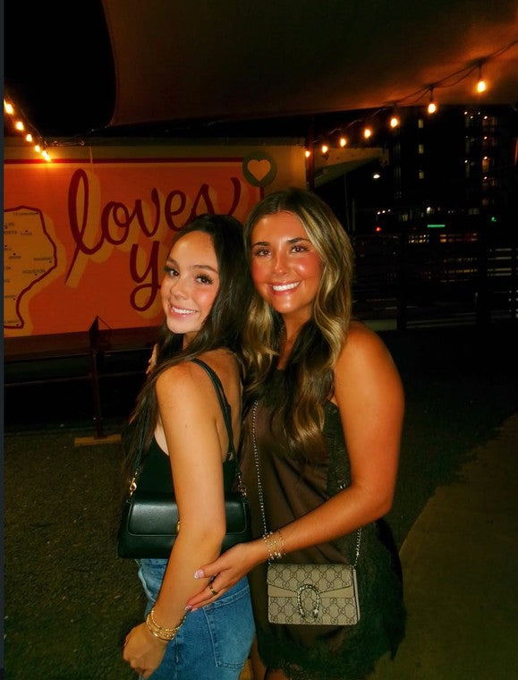 Two friends posing at night under the string lights