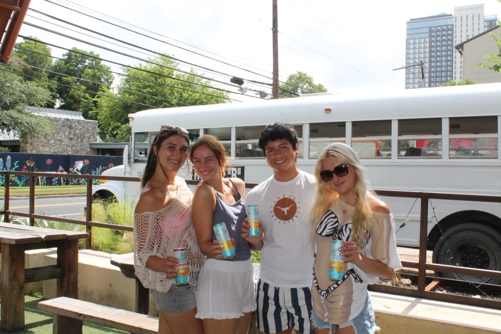 Four friends sharing Sun Cruisers by the parked bus