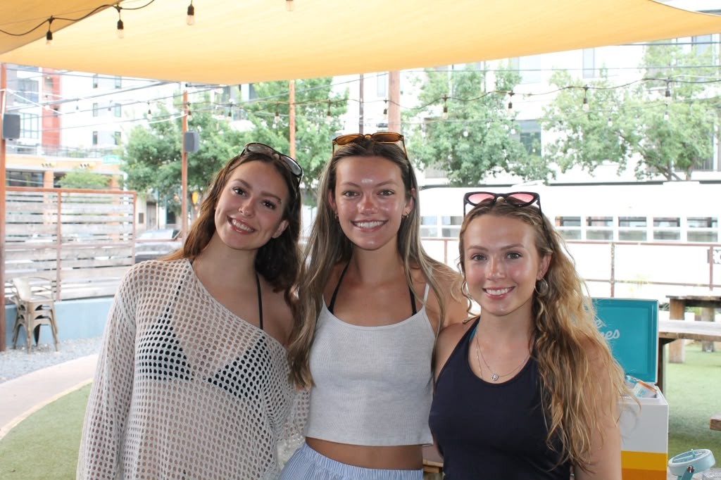 Three friends smiling together under the patio shade sail